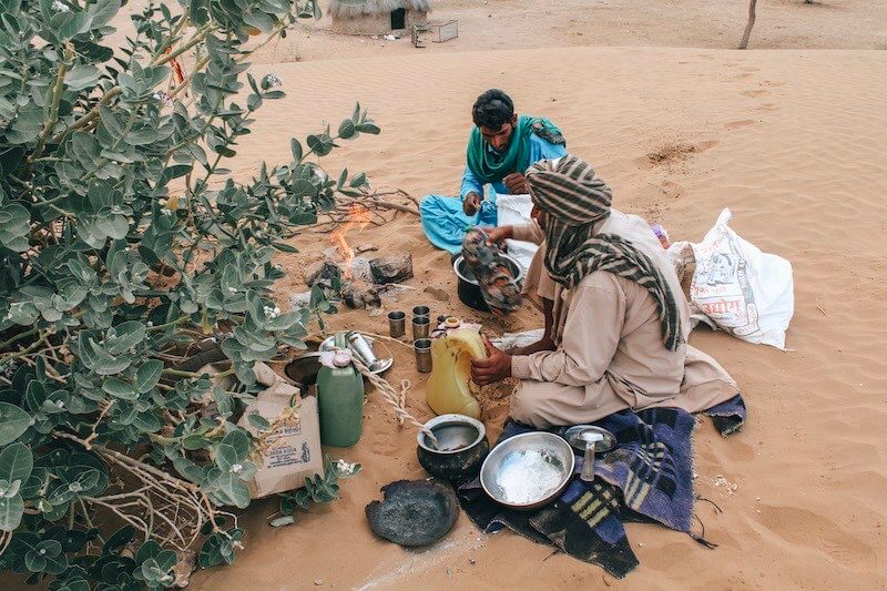 backpacker - two guys cooking in the sand in the desert of India