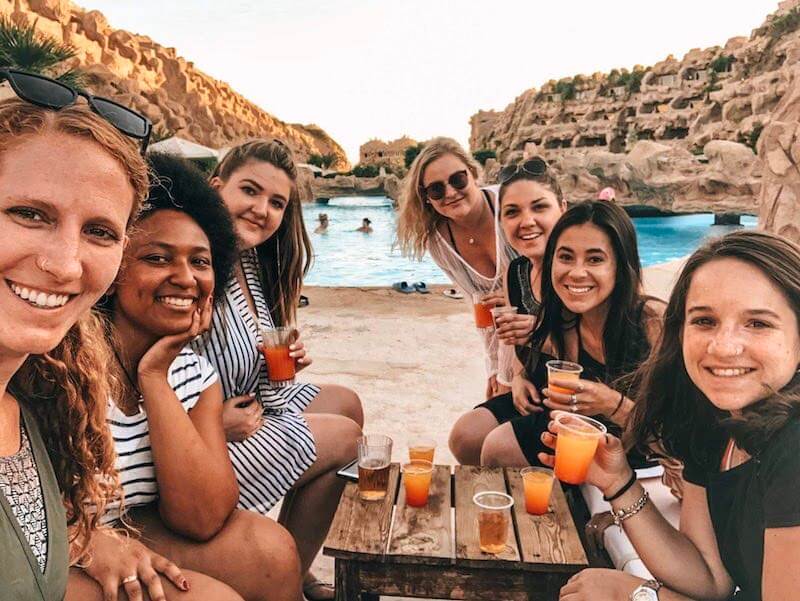backpacker - groups of girls posing with cocktails at a resort pool in egypt