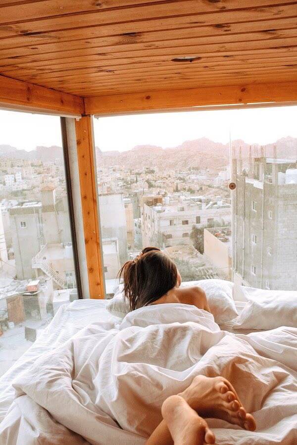 backpacker - girl in bed in a glass windowed hostel pod overlooking Petra Jordan