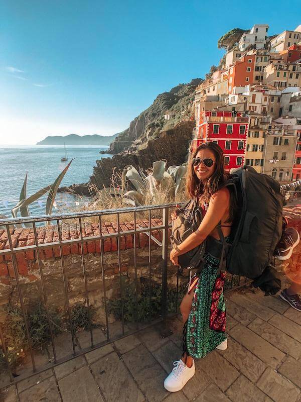 travel the world - girl wearing a travel backpack overlooking ocean in italy