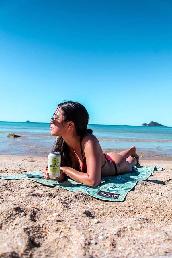 packing list - girl laying on tesalate sand free beach towel