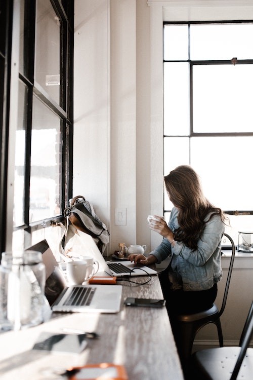 plan solo trip - girl working on laptop at cafe